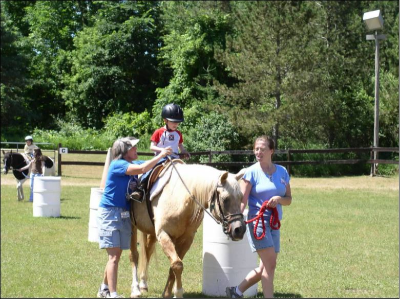 志愿者带领一名青年骑马。